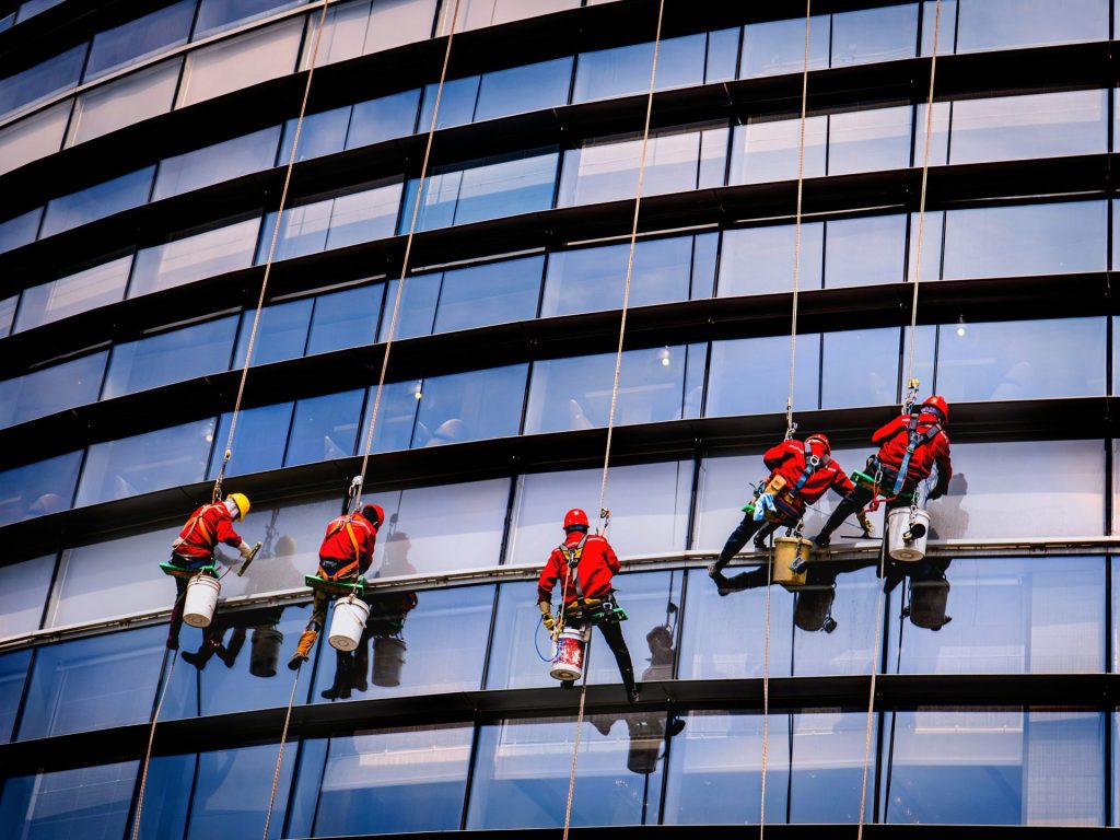 Fensterputzer reinigen die Außenfassade eines hohen Gebäudes.